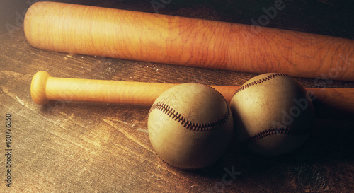 Two baseballs and bats on wooden table