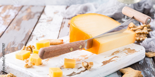 Photos Delicious dutch gouda cheese with cheese blocks, crackers, walnuts and special knife on old wooden table