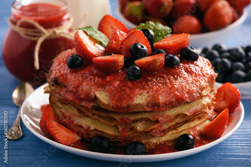 Stack of homemade pancakes with strawberry mousse and berries.