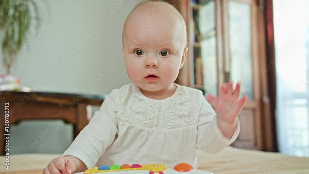 Baby sitting on the bed and playing with a toy. Medium shot. Soft focus Baby sitting on the bed and playing with a toy. Medium shot. Soft focus