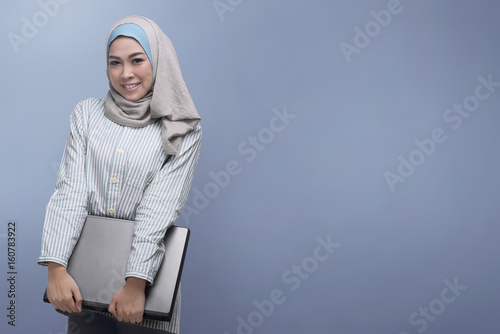 Young asian muslim woman holding laptop