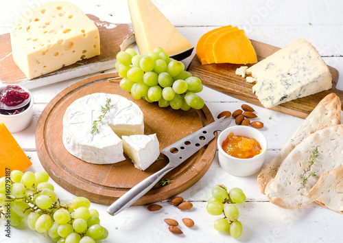 Different kinds of cheeses on white wooden table