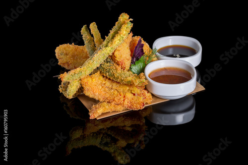 Tempura vegetables on a black background with reflection