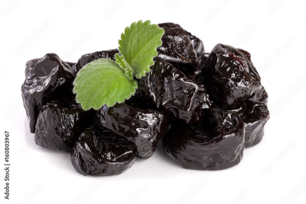 heap of dried plums or prunes with a mint leaf isolated on white background