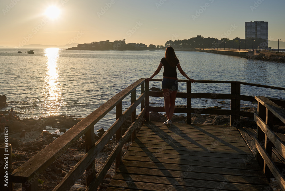 Chica joven apoyada en un mirador junto al mar