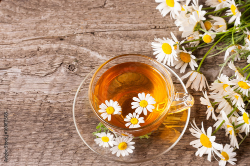 Herbal tea with fresh chamomile flowers on old wooden background with copy space for your text