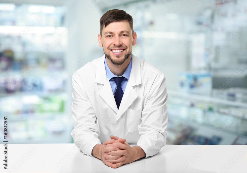 Young handsome pharmacist standing at table on white background Young handsome pharmacist standing at table on white background