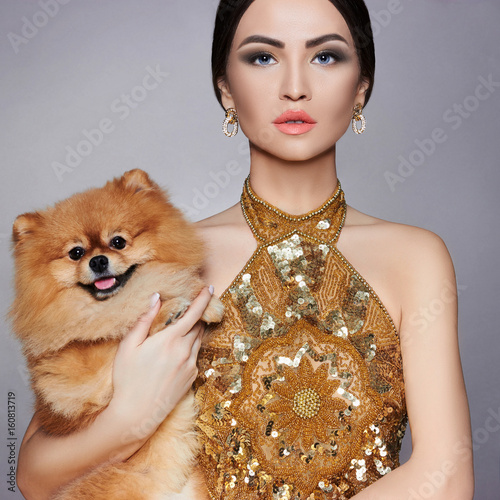 Portrait of a fashion model with a small dog in his hands
