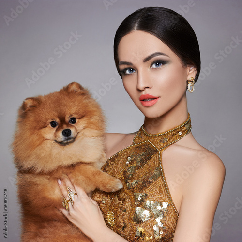 Portrait of a fashion model with a small dog in his hands