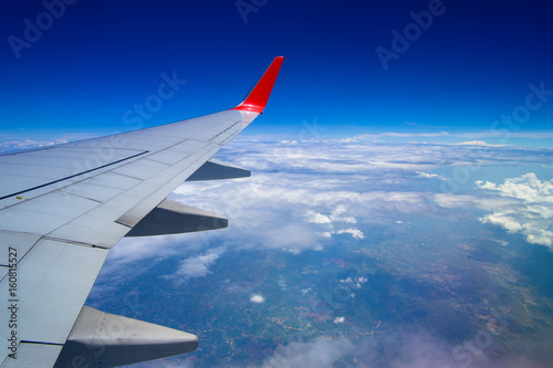 Aerial view from airplane window. Airplane flying above land with beautiful clouds in the sky