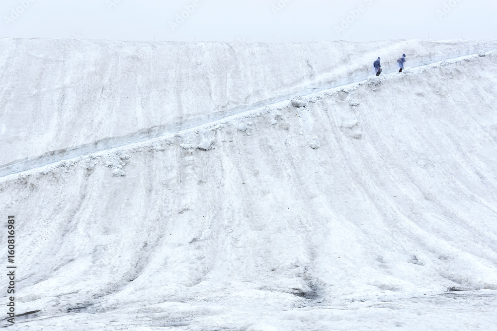 Hiker walking uphill on path in the snow Hiker walking uphill on path in the snow