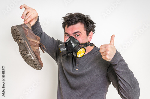 Man with gas mask is holding stinky shoe