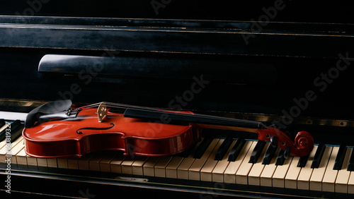 Classical musical stringed instrument violin on piano keys.  Fiddle on piano keyboard. photo