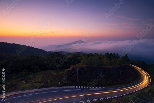 Mountain fog and light line on the road from cars during the sunrise