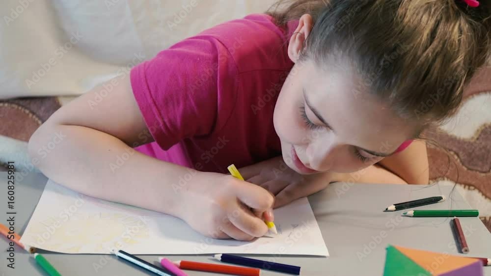 Girl at the table draws in colored pencils Girl at the table draws in colored pencils