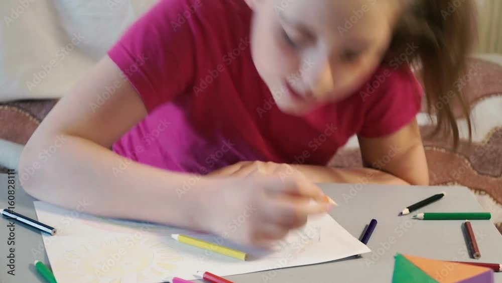 Girl at the table draws in colored pencils Girl at the table draws in colored pencils