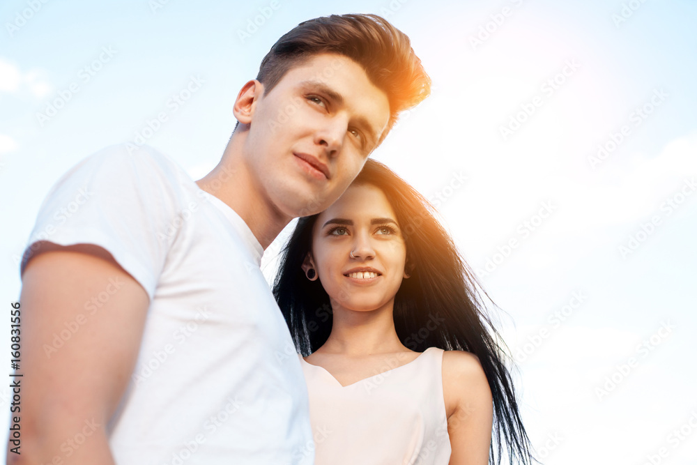 The guy and the girl with the perfect smile, laugh and look forward in the background of a Sunny day. Beautiful young couple during a romantic date. The guy and the girl with the perfect smile, laugh and look forward in the background of a Sunny day. Beautiful young couple during a romantic date.