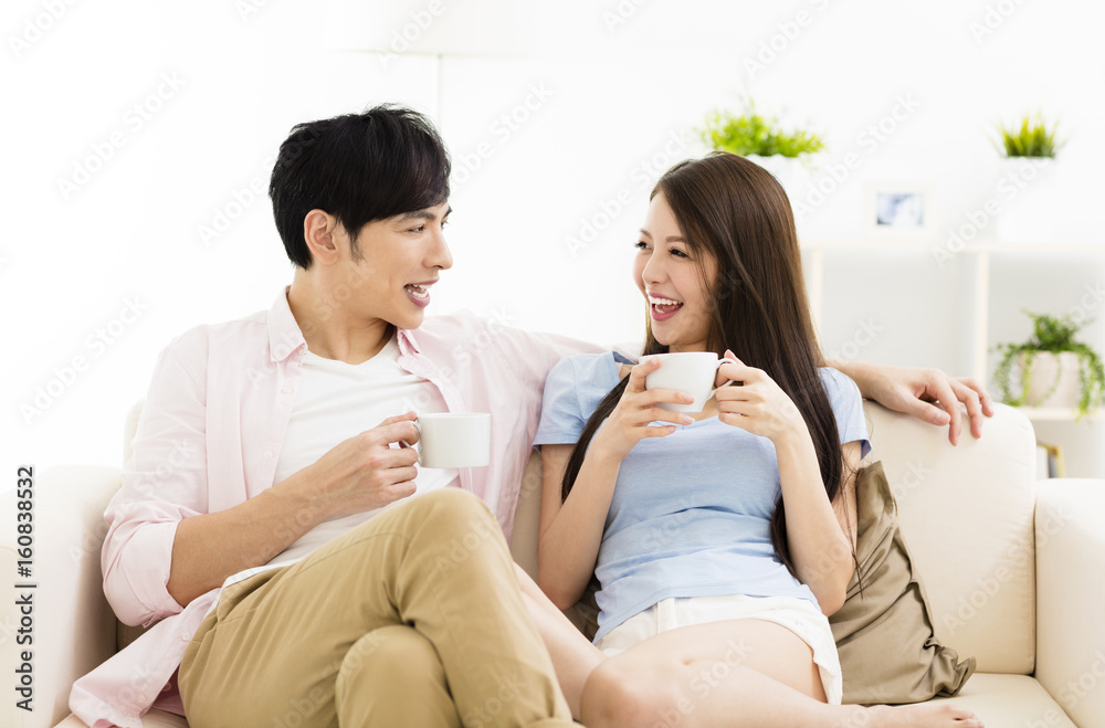 Portrait of smiling young couple sitting on sofa Portrait of smiling young couple sitting on sofa