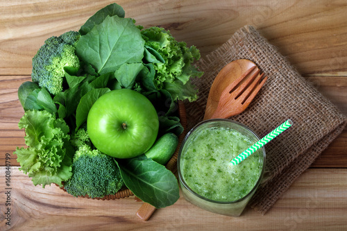 Fototapeta Naklejka Na Ścianę i Meble -  close up green apple with mixed green vegetable and green juice in a basket and wooden fork and spoon for healthy organic green food concept