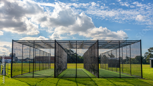 A row of cricket pratice nets on green grass and with a blue sky in Melbourne, Victoria, Australia photo