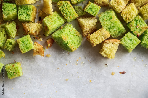 Home made green croutons on white surface