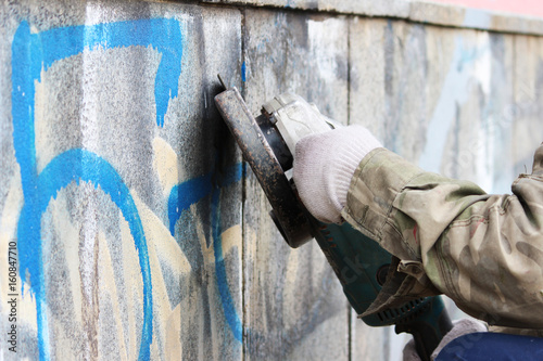 Removal of graffiti on a concrete wall of an underground passage with the help of a angle grinder. photo