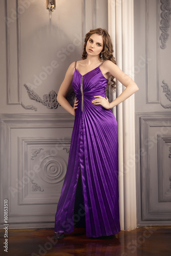 the girl in purple evening dress on background of vintage wall