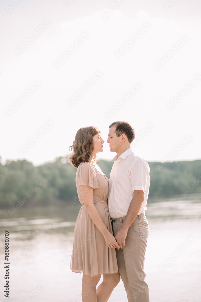 beautiful couple a man and a woman in bright clothes, happy family, walking along the river Bank,standing holding hands, looking at each other, hugging, summer,