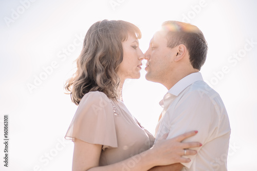 beautiful couple, the girl in the beige dress, the man in the white shirt, kiss on the background of sky, sun, close-up, summer, heat, nature, love story