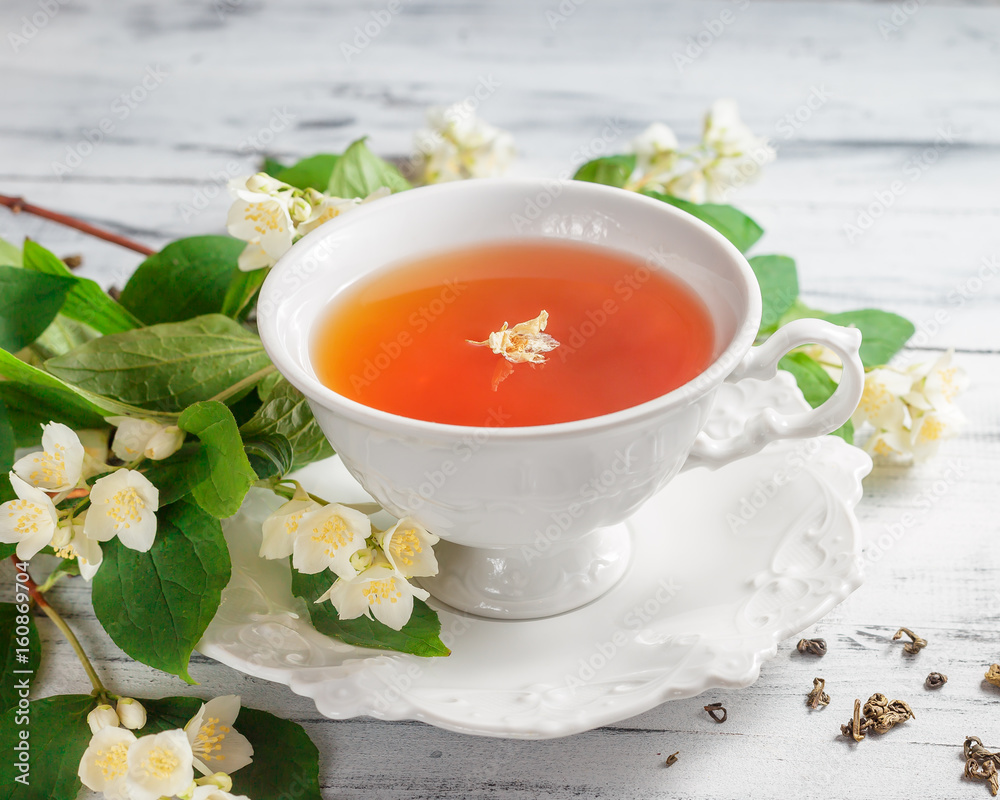 Cup of tea with jasmine flowers on a white table Cup of tea with jasmine flowers on a white table