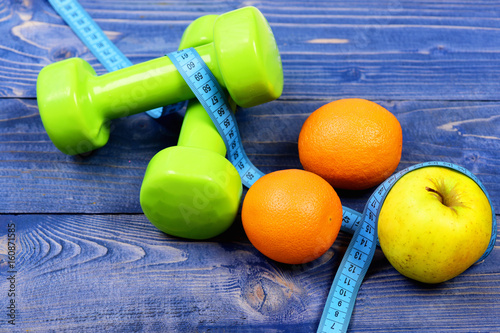 weight dumbbells with measuring tape, apple, orange for diet concept