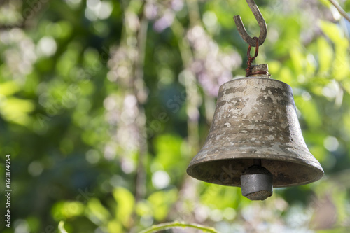 Small metallic oriental bell in the garden, sunny day, greenery