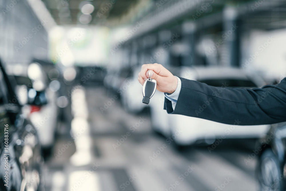 Giving a key from new car at dealership showroom Giving a key from new car at dealership showroom