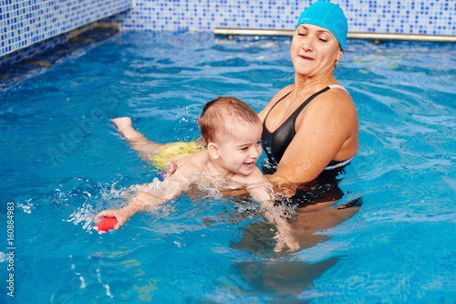 Healthy family, mother teaching baby swimming pool