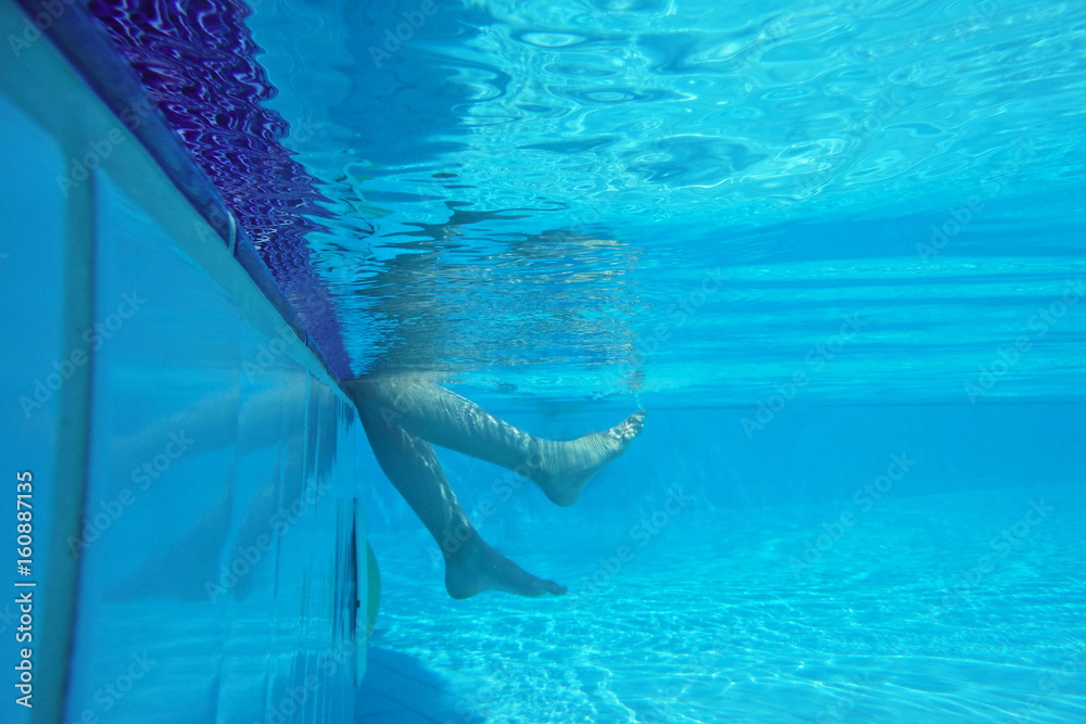 Underwater shot of legs playing on pool border