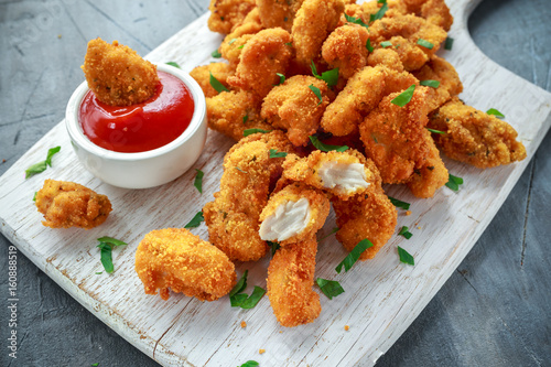 Fried crispy chicken nuggets with ketchup on white board photo