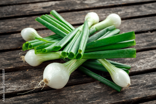 Raw Bunch of fresh spring onion on rustic wooden table