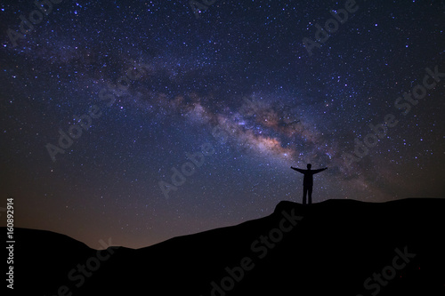 Landscape with milky way, Night sky with stars and silhouette of happy people standing on the mountain, Long exposure photograph, with grain