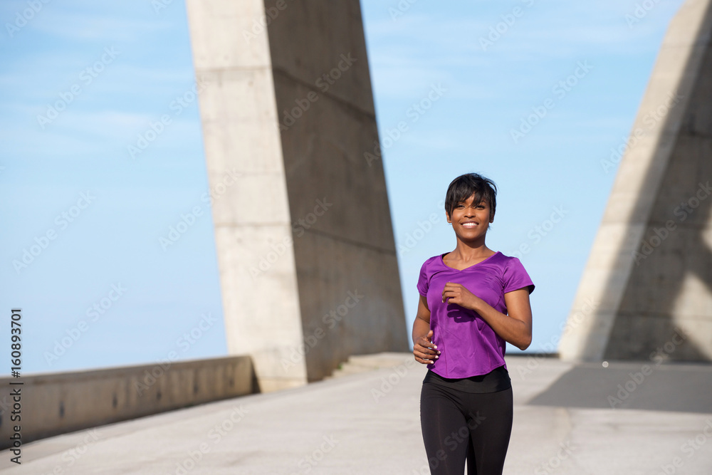 Fototapeta premium Beautiful young african american lady running outdoors.
