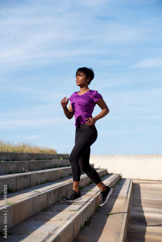 Fit young african woman running up stairs