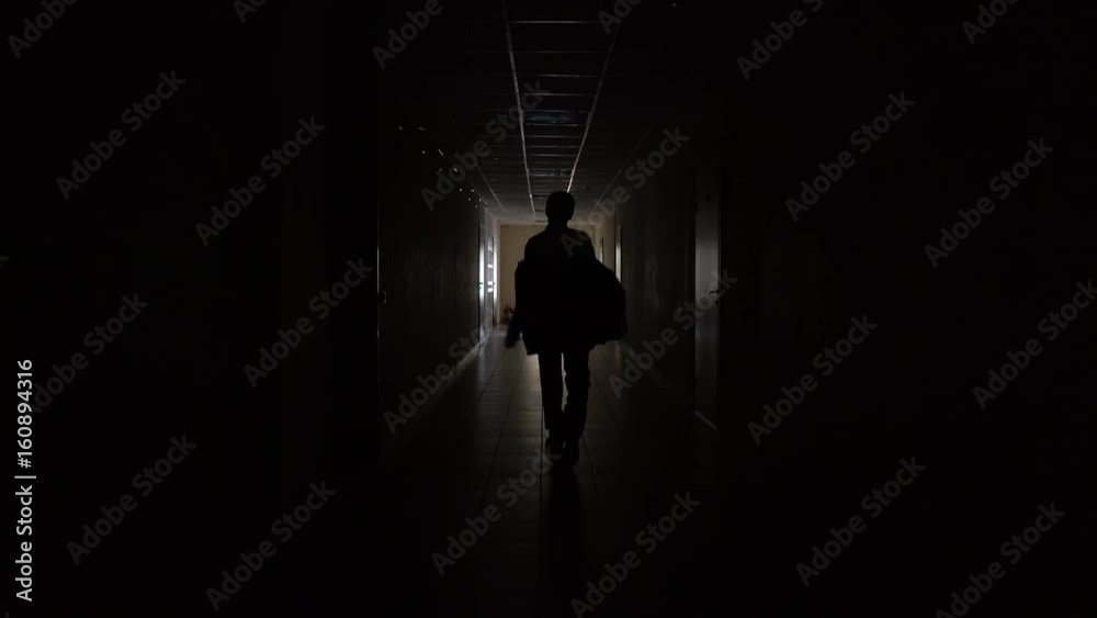 Silhouette of a man runs through the dark corridor. Dismissal.The Ghost of a businessman .The path to success. Silhouette of a man runs through the dark corridor. Dismissal.The Ghost of a businessman .The path to success.