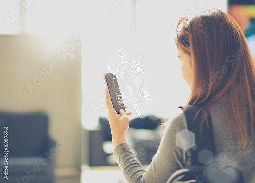 A asian woman using smartphone with IOT, internet of things sign and icon. Digital era or omni channel concept. Internet on everyday.