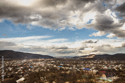 Incredible sky in the mountains with falling clouds, hanging over the village in sunlight reflections