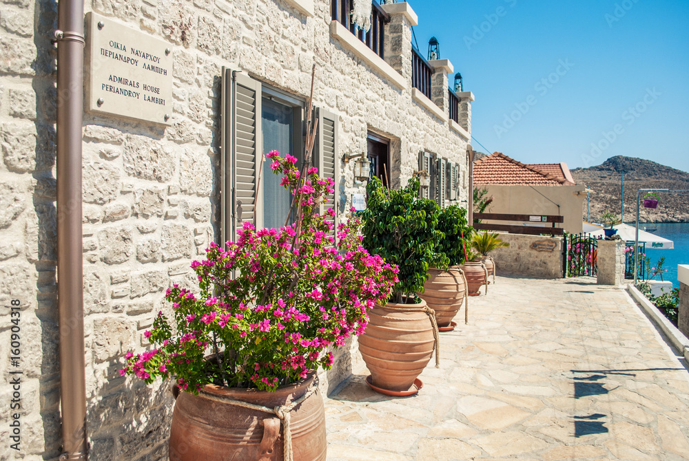 Chalki, Greece - September 01, 2015: Sea view with traditional flowers near the greek house.