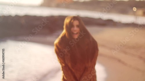 Fashion model playing with long hair with dress on beach at sunset slow motion