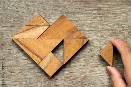 Tangram puzzle in heart shape wait to fulfill with triangle shape on wooden background