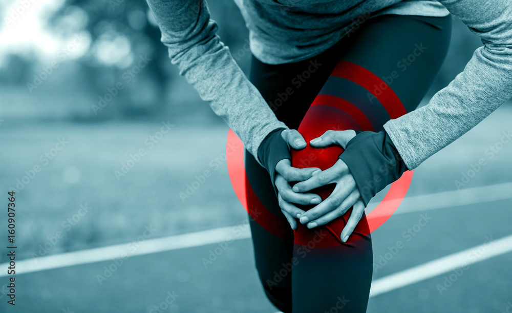 Athletic woman on running track touching hurt leg with knee injury