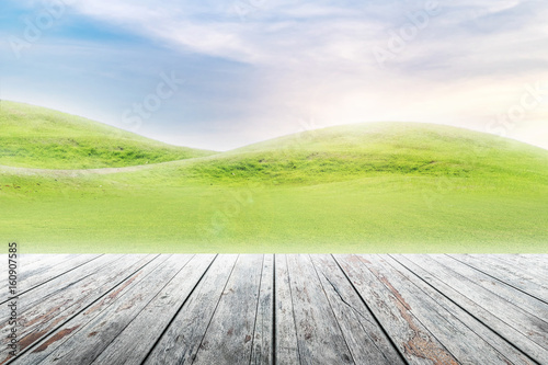 Wood table top on mound slope green grass natural background in morning time.