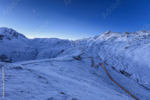 Blue light of dusk on the snowy landscape and the hairpin turns of Stelvio Pass Braulio Valley Valtellina Lombardy Italy Europe photo