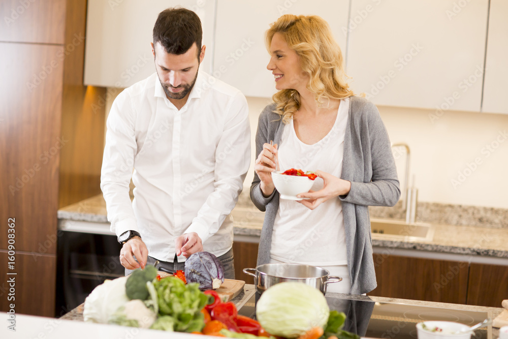 Man helping his girlfriend cooking in modern kitchen Man helping his girlfriend cooking in modern kitchen